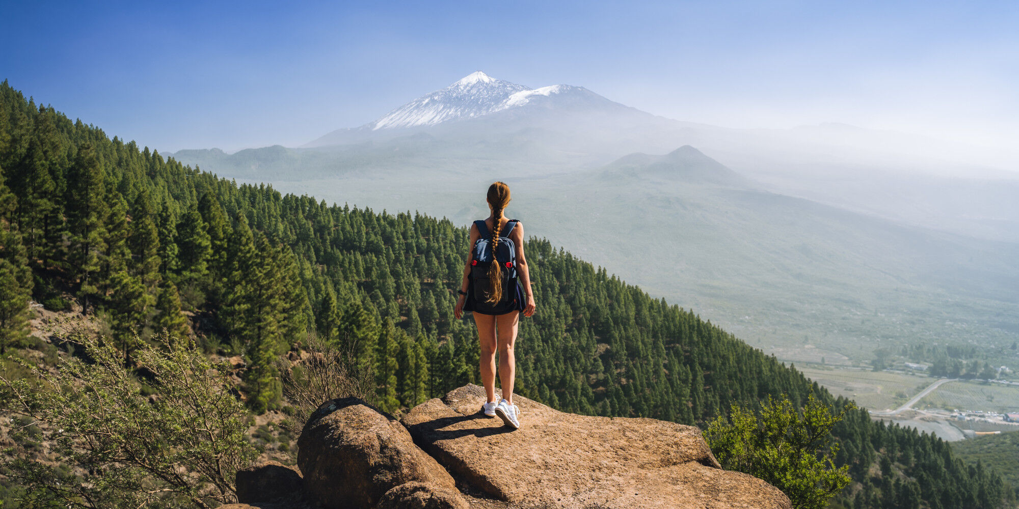 Wanderin auf einem Vorsprung vor den Bergen
				        