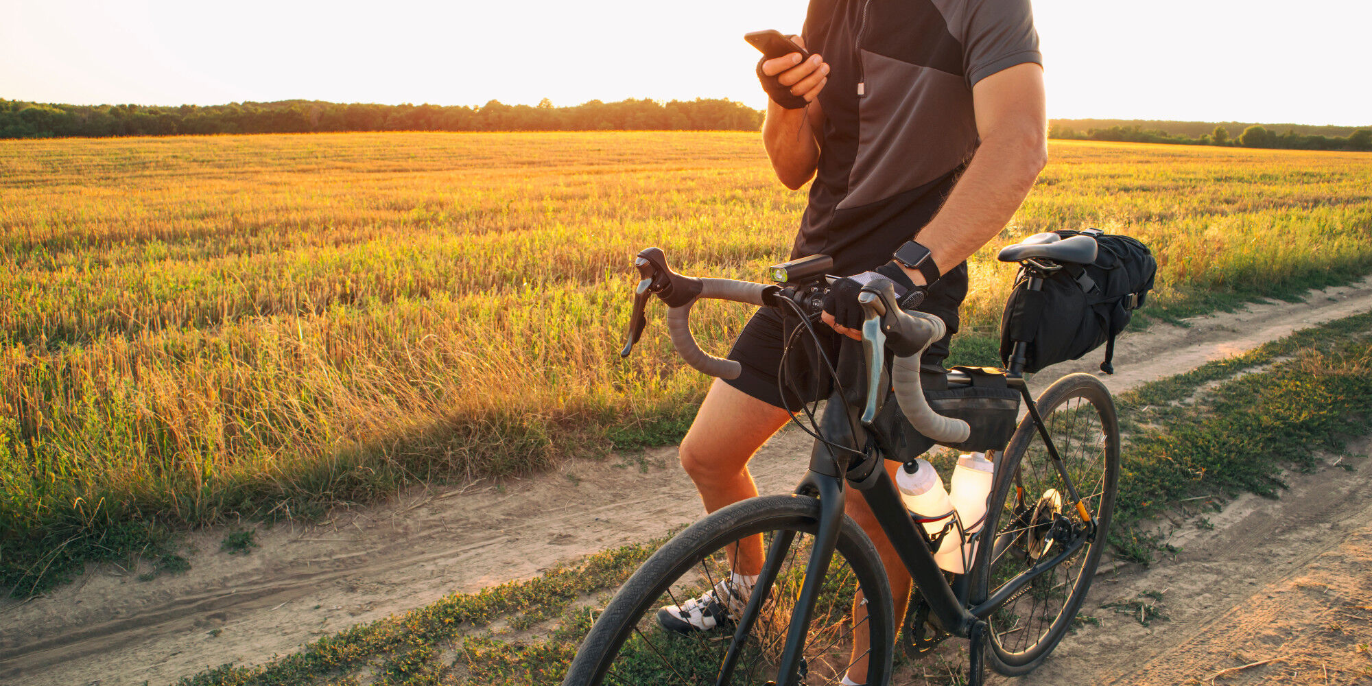 cycliste dans les champs avec des sacoches et une montre connectée
				        