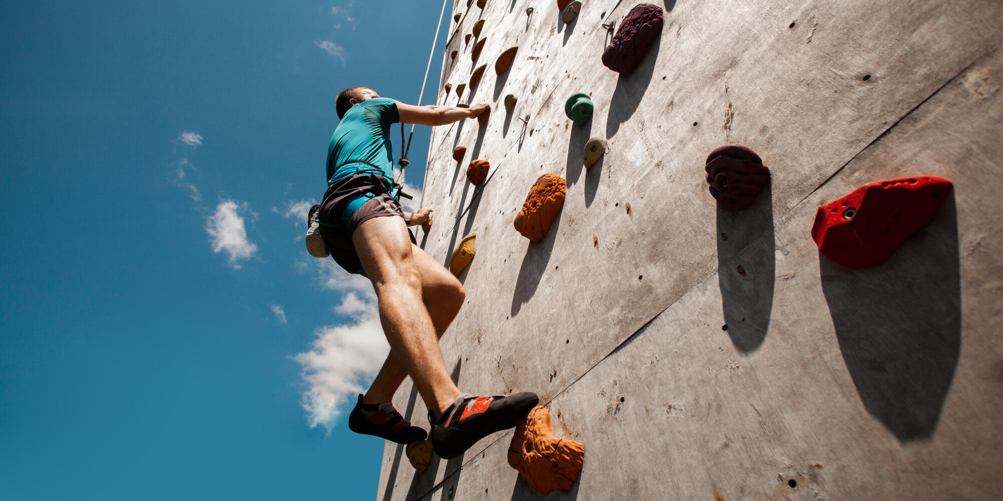 homme qui escalade avec un baudrier et des chaussons d'approche
				        