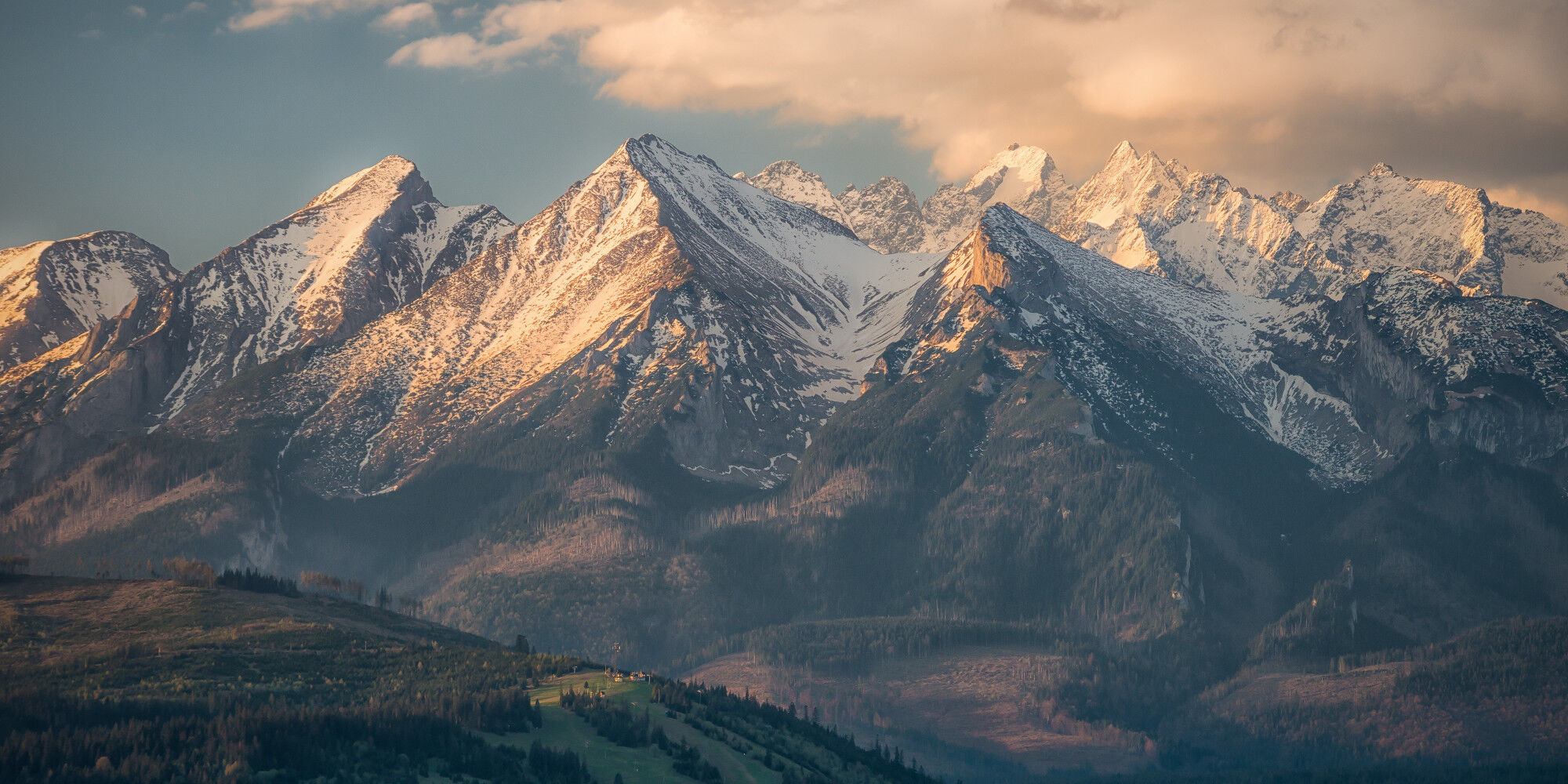 mountains with snow on the heights and forests
				        