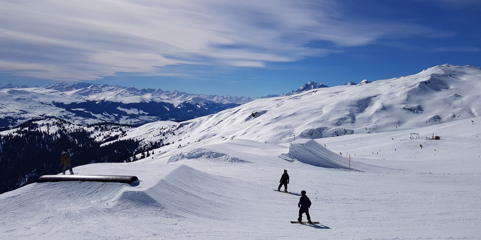 pistes en montagne avec deux snowboarders et la forêt
				        