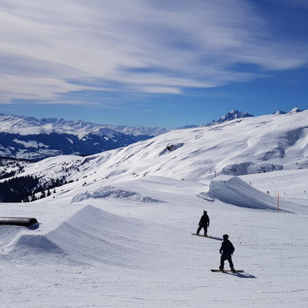 pistes en montagne avec deux snowboarders et la forêt