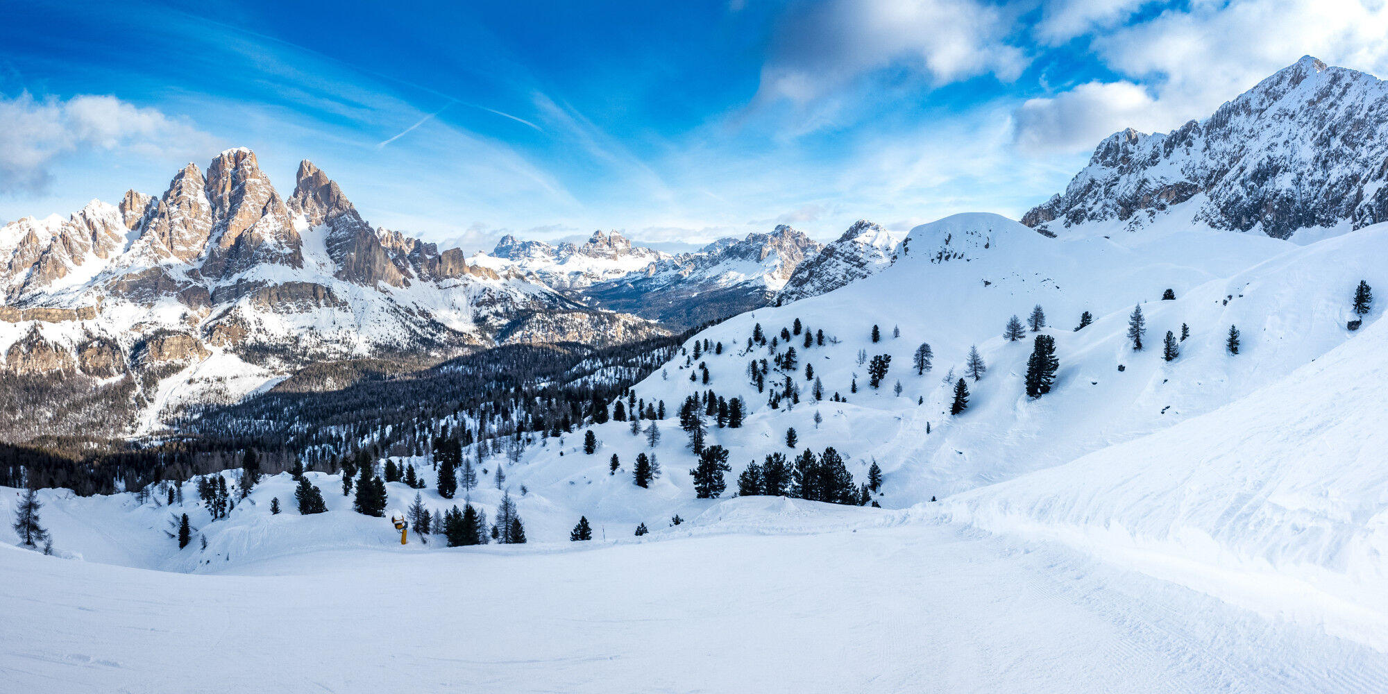 pretty snow-covered mountain with fir trees and blue sky
