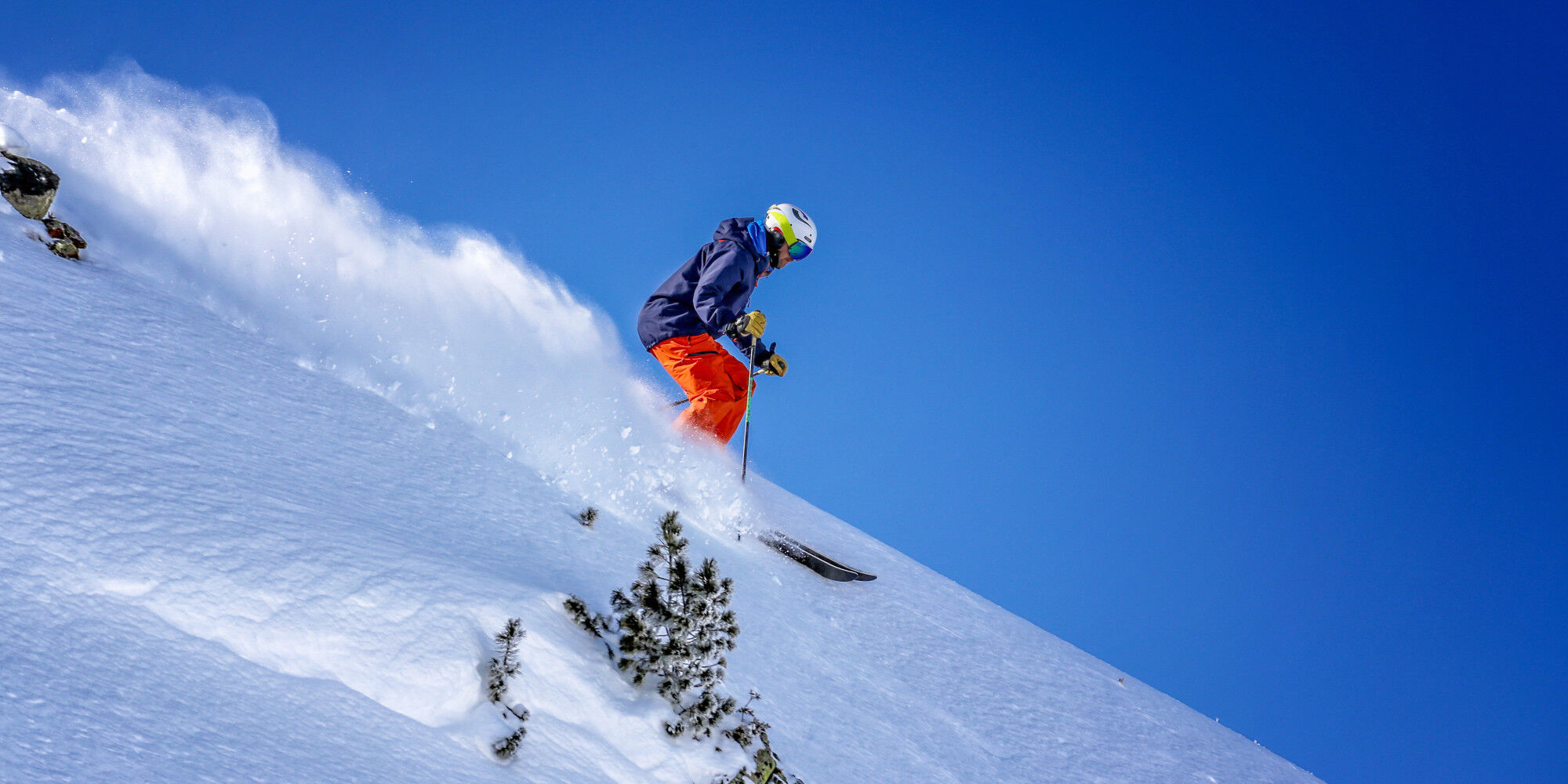 skieur dévalant la montagne en faisant un nuage de neige
				        
