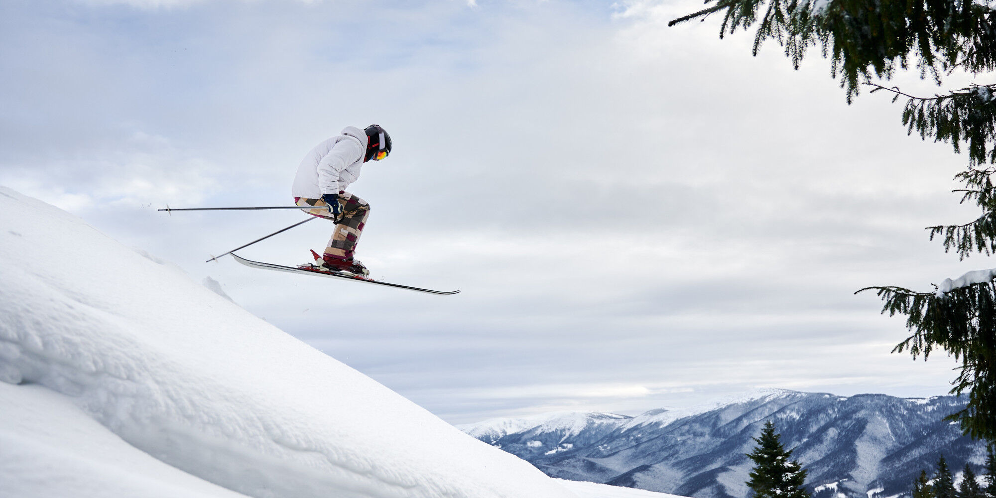 skier flying over the hump with a mountain in the background
				        