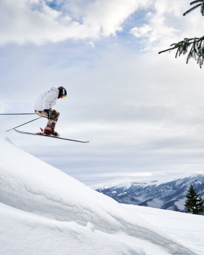 skier flying over the hump with a mountain in the background
			                        