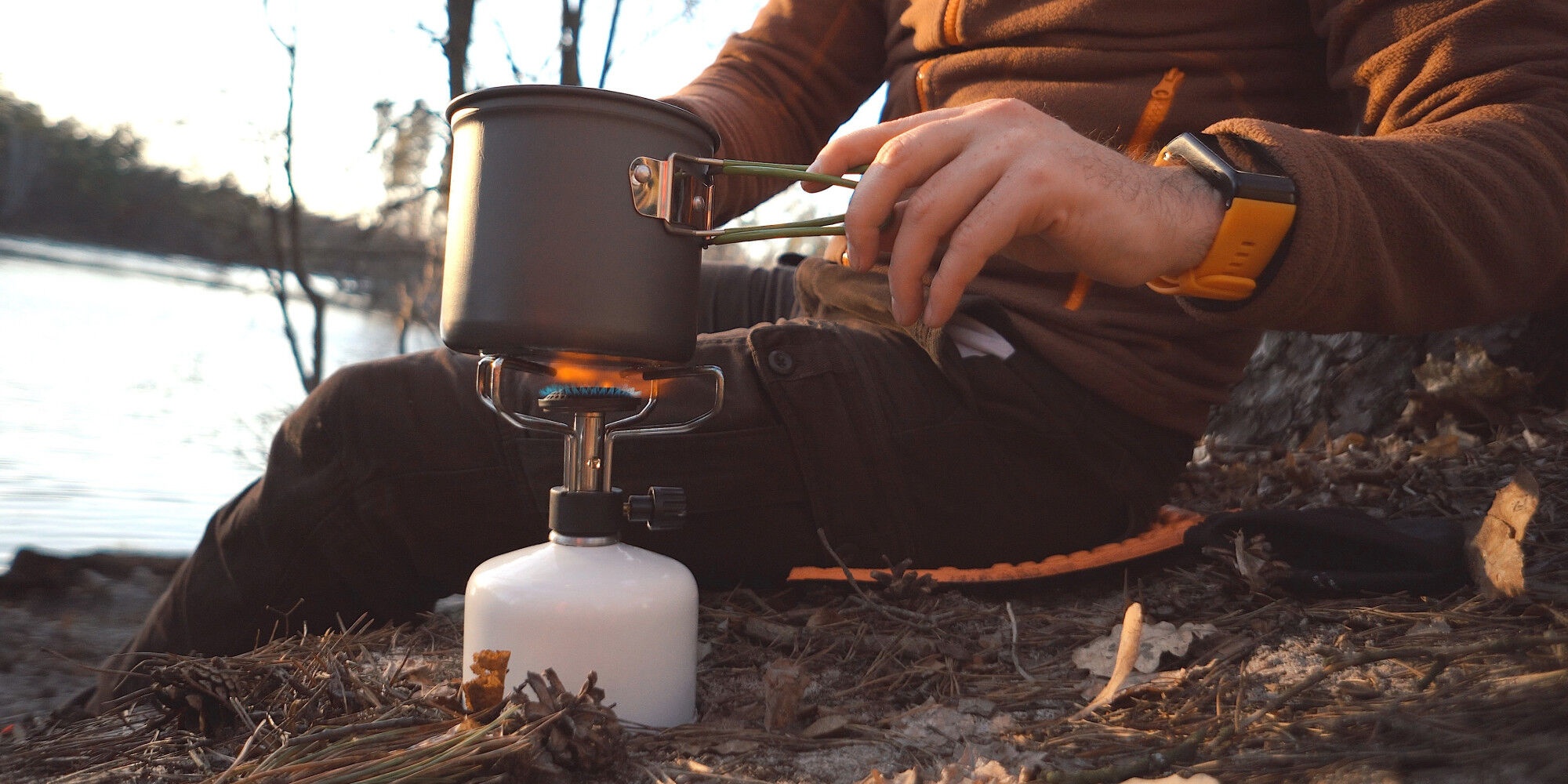 campeur qui utilise un réchaud au gaz et une popote
				        