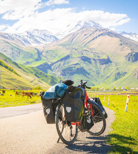 Bicycle with panniers on a mountain road
			                        