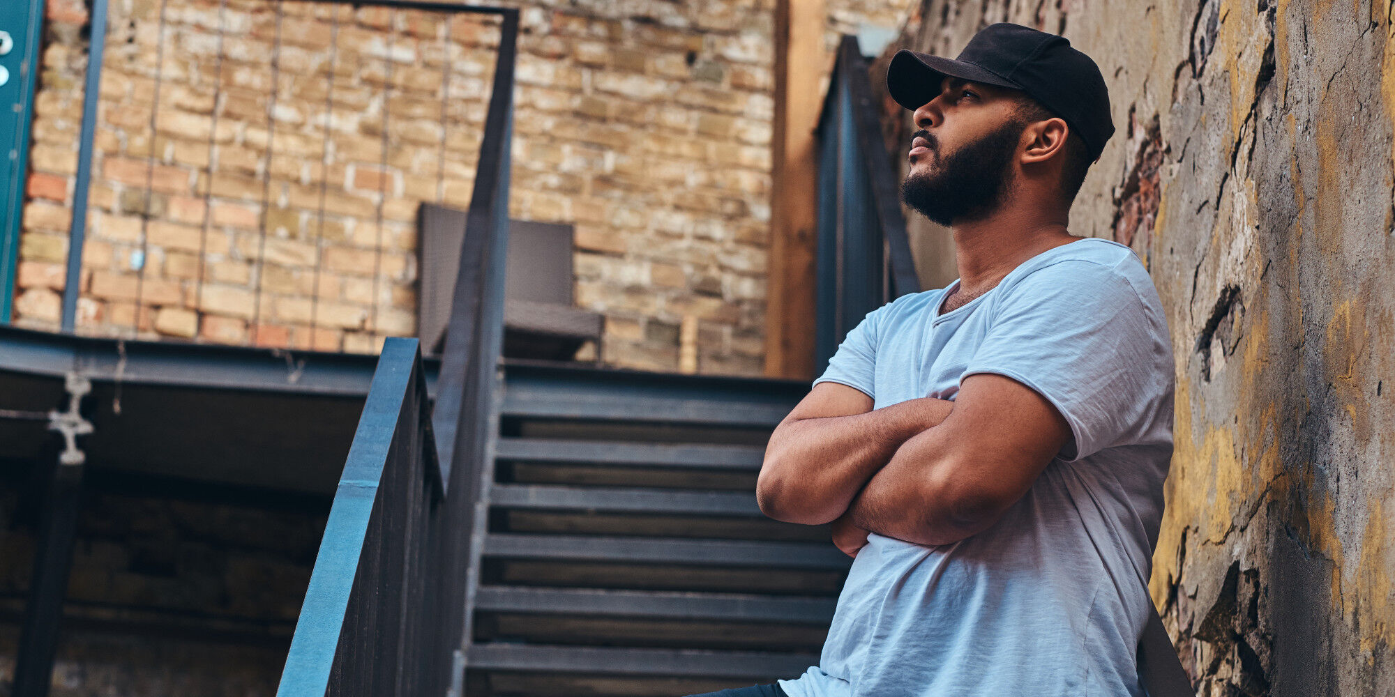 homme contre un mur avec une casquette sportswear
				        