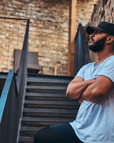 homme contre un mur avec une casquette sportswear
			                        