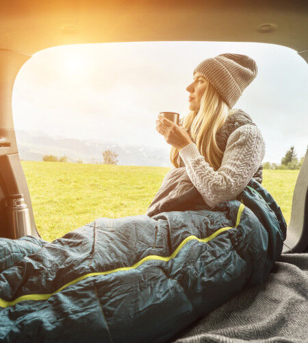 femme dans un sac de couchage en van life
			                        