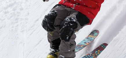 skier descending a steep slope in freestyle with a ski helmet