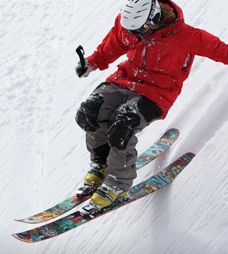 skier descending a steep slope in freestyle with a ski helmet
		                        