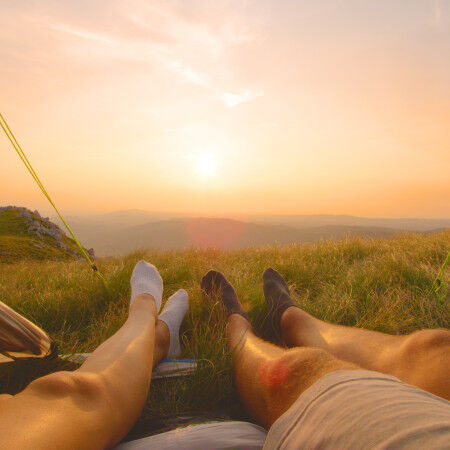 LENS FLARE: Uomo e donna in escursione estiva si rilassano e guardano l'alba.