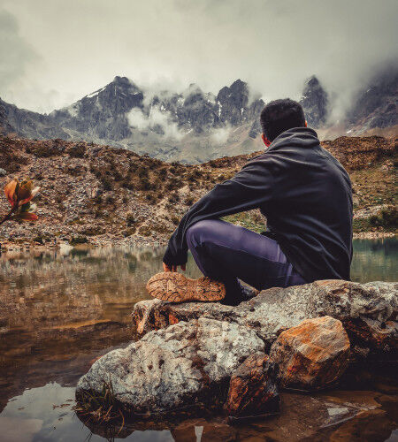 homme assis sur un rocher en montagne
			                        