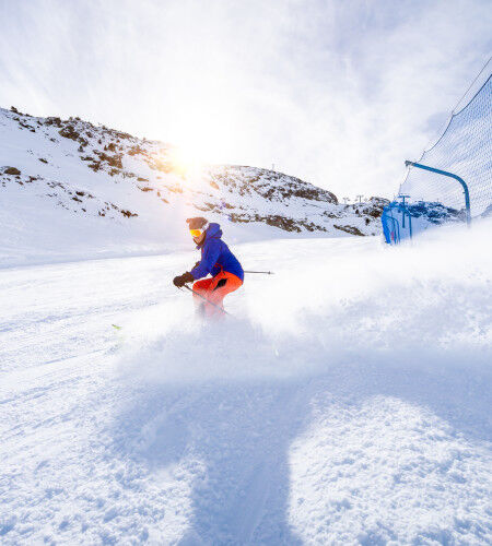 Skifahrer, der eine Piste hinunterfährt
		                        
